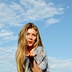 Second pic of Busty natural blonde April E poses in a field and shows us her insanely hot and curvy bod