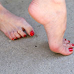 Second pic of Brunette Mary Jane in black skirt and red blouse exposes her feet outdoors