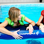 Third pic of Rachel Evans and Nessa Devil admire each others legs on the edge of the pool and swim clothed