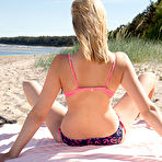 Second pic of Nude Agatha displays her big titties as she strips on the sand.