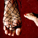 Second pic of Big meloned brunette Sunny Leone exposes her feet and pussy with her fishnet pantyhose on
