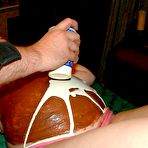 Second pic of Pregnant chick has her belly bump decorated with food on a table