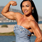 Third pic of Asian bodybuilder Tram Nguyen flexes in the outdoors while wearing dresses