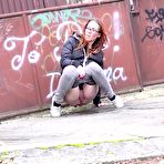 Third pic of Redheaded girl pulls down her pants to take a piss in front of steel gates