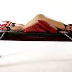 First pic of Blonde Mistress in latex clothing forces a slave to orgasm on bondage table